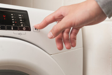A person is pressing a button on a white washing machine