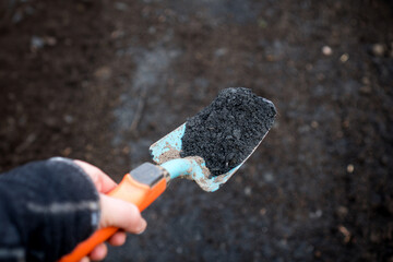 Close-up of biochar on a shovel, illustrating sustainable permaculture soil enhancement with Terra...