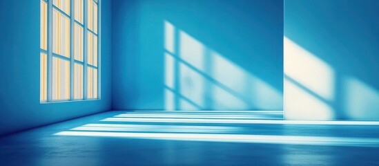 Obraz premium Sunlight streams through a window in a blue room casting shadows on the floor.