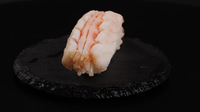 Shrimp sushi or Japanese ebi sushi set on black plate with wasabi in flash lighting.