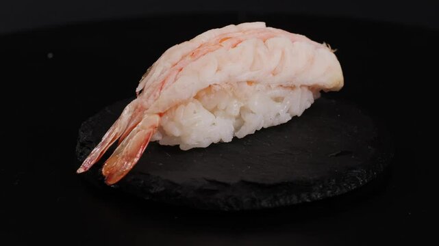 Shrimp sushi or Japanese ebi sushi set on black plate with wasabi in flash lighting.