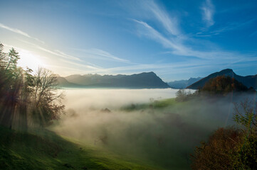 Swiss panorama with mountain Fronalpstock in Swiss alps, Canton Schwyz, Switzerland, with rising sun in fall above clouds