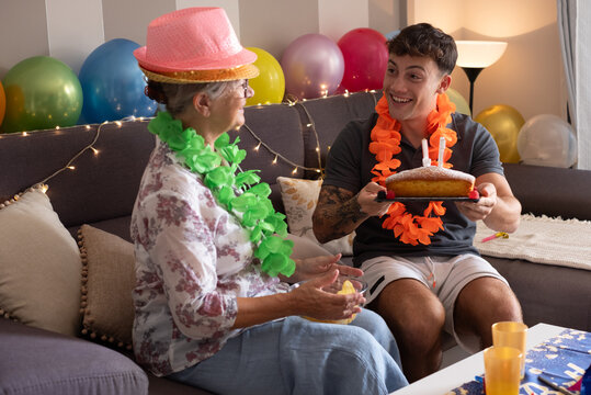 Happy Multi-Generational Family Couple of Grandmother and Grandson Celebrate Grandmother's 70th Birthday sitting on home sofa