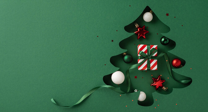 A green paper Christmas tree cutout adorned with red and white ornaments, stars, and a wrapped gift, conveying a festive holiday atmosphere and creative design