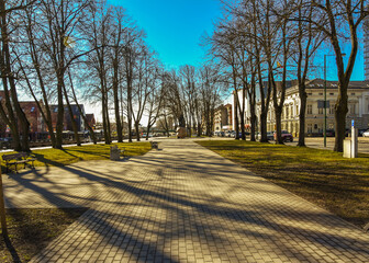 A brick walkway in a serene park with trees offering shade