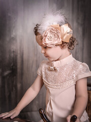 Cute girl in a stylish blouse with lace and feathers on her head, focused on something