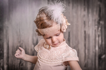 Cute girl in a stylish blouse with lace and feathers on her head, focused on something