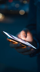 Close up of hand holding smartphone, glowing screen in dark setting Vertical Mobile Wallpaper