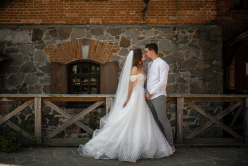Stone building backdrop as groom and bride exchange a kiss
