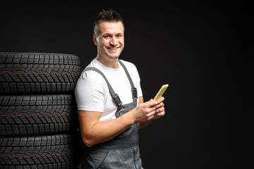 Mechanic using mobile phone next to stack of tires