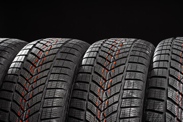 Fototapeta premium Close up of winter car tires standing on black background