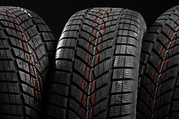 Set of winter tires standing on black background showing tread pattern