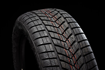 Winter car tire showing tread pattern on black background © Maria Vitkovska