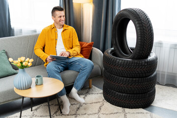 Man choosing tires online using tablet, sitting on sofa at home © Maria Vitkovska