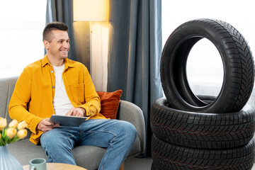 Mechanic browsing online tire shop on tablet with tires in background © Maria Vitkovska
