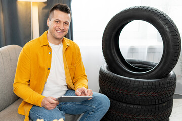 Mechanic using digital tablet while sitting next to tires