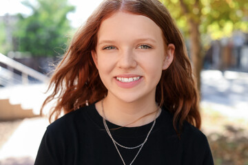 Portrait of happy teenage girl with long hair outdoors