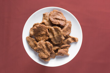 Overhead view of kuli-kuli on a white plate, top view of nigerian groundnut cakes on a plate, fresh homemade nigerian kulikuli on a ceramic plate