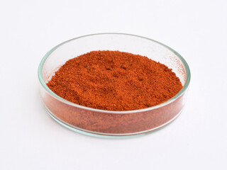 Paprika (ground red pepper) in a petri dish, white background