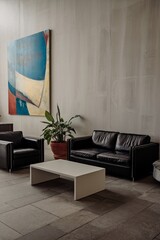 Modern Minimalist Lounge: Sophisticated interior design featuring a sleek black leather sofa and armchairs, complemented by a contemporary abstract painting and a simple coffee table.