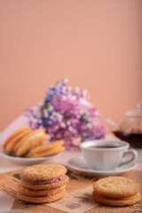 photoDelightful Afternoon Snack Arrangement Featuring Homemade Cookies with Tea and Colorful Floral Decor on a Cozy Table Setting for a Relaxing Break