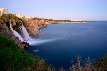 Fototapeta premium Scenic Waterfall Flowing Over Rocky Cliff A stunning waterfall cascading over a rocky cliff surrounded by greenery, creating a serene and natural outdoor scene.