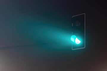 Green traffic lights in a foggy night.