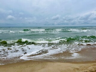 cloudy grey seascape, waved sea horizon, windy at the sea, empty beach