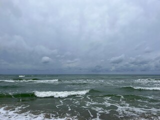 cloudy grey seascape, waved sea horizon, windy at the sea, empty beach