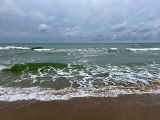 cloudy grey seascape, waved sea horizon, windy at the sea, empty beach