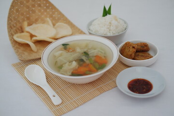 Creamy soup in a white bowl, with delicious side dishes