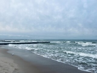 cloudy grey seascape, waved sea horizon, windy at the sea, empty beach