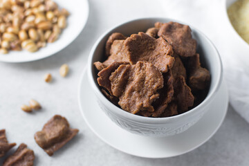 Overhead view of kuli-kuli and roasted peanuts on a white plate, top view of nigerian groundnut cakes and groundnuts on a plate