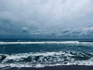 cloudy grey seascape, waved sea horizon, windy at the sea, empty beach