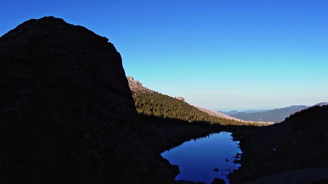 Sliding shot revealing Lincoln Lake behind a dark boulder in the evening in the Mount Evans Wilderness (Now Mt. Blue Sky Wilderness), Colorado