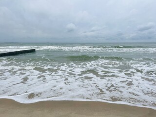 cloudy grey seascape, waved sea horizon, windy at the sea, empty beach