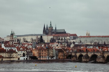 Scenic view of Prague Castle and Charles Bridge over Vltava River on a cloudy day