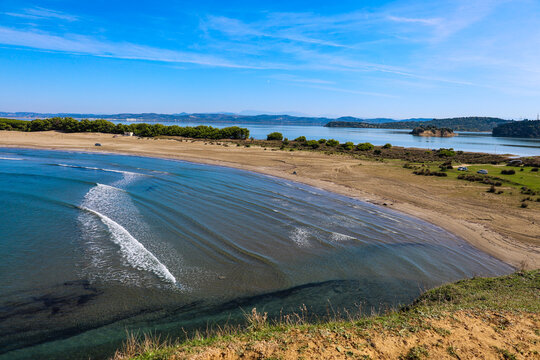 view from a lookout on a hill above the deserted Zv&euml;rnec beach in Albania with the waves of the rippling sea, Zv&euml;rnec island and Narta lagoon in the background