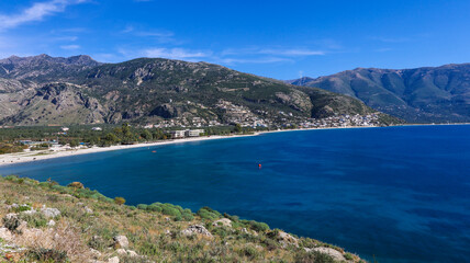 bird's eye view of the wide coast of the Albanian Riviera and its longest beach, Borsh, with a white beach, blue sea and mountains in the background
