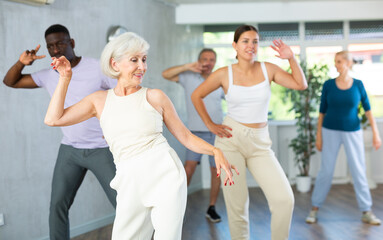 Group of multinational sports aged people rehearsing modern dance in dance hall