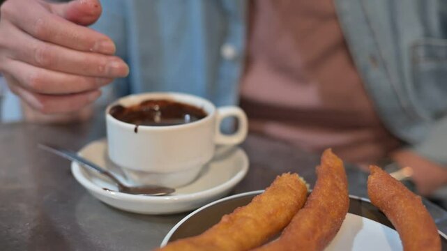 Elderly man with Parkinson's enjoying churros and chocolate, savoring a moment of indulgence