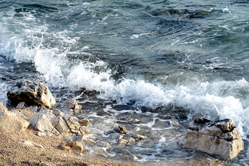 Clear sea water with big splashing and foamy wave that hitting the pebble beach © Happy window