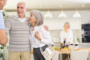 Obraz premium Two elderly couples meet for a holiday dinner at home. Greet each other