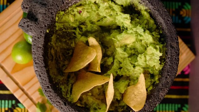  Mexican guacamole in a molcajete, top view of slowly rotating camera, typical food for national holidays