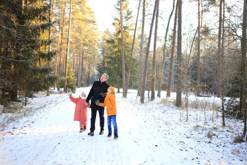A father enjoys a leisurely walk with his two children through a beautiful snowy forest. The scene captures the joy of family time amidst the serene winter landscape, with snow-covered trees creating
