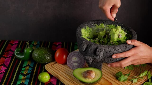 Mexican guacamole, a Mexican woman prepares guacamole in a stone molcajete