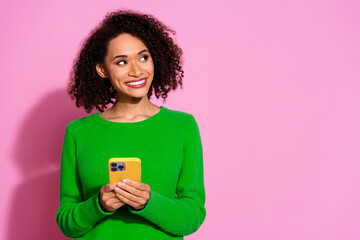 Photo portrait of attractive young woman hold device look empty space dressed stylish green clothes isolated on pink color background