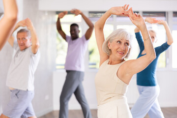 Group of multinational sports aged people rehearsing classical dance in dance hall