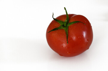 Freshly harvested red tomato on a white background showcasing natural shine and texture in detail