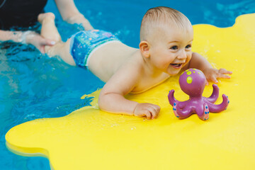 A child learns to swim in a pool with a coach. Teaching children to swim.